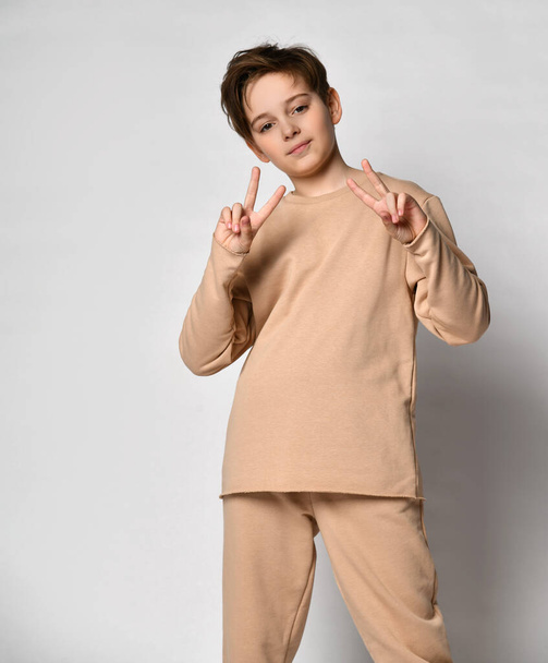 Portrait of preteen boy showing v-sign gesture raising two hands - Photo, image