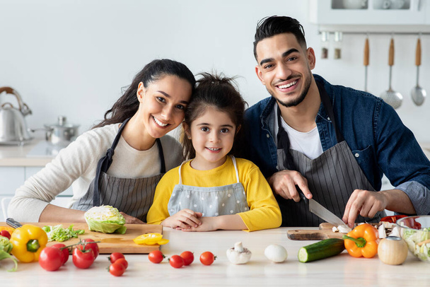 Πορτρέτο της ευτυχούς οικογένειας της Μέσης Ανατολής με μικρή κόρη μαγείρεμα στην κουζίνα - Φωτογραφία, εικόνα