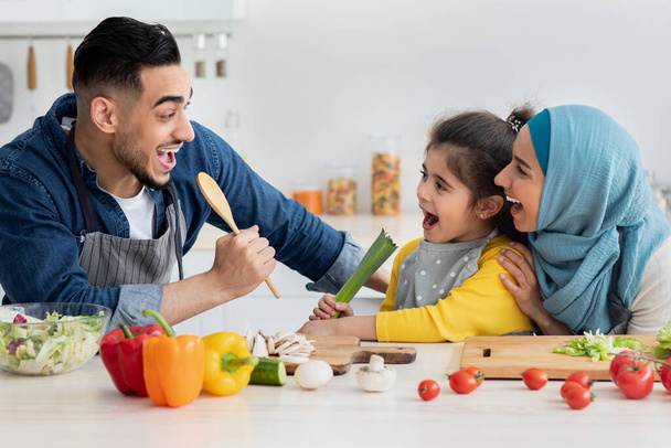 Veselý islámské rodiče baví s malou dcerou při vaření v kuchyni - Fotografie, Obrázek