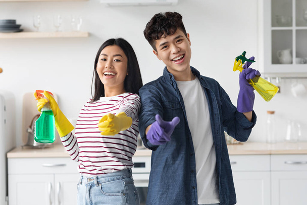 Веселые азиатские домовладельцы позируют во время уборки кухни - Фото, изображение