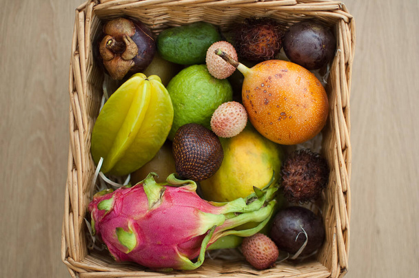 Big basket of fresh tropical fruits, passion fruit, carambola, dragon fruit or pitaya, mangosteen, lichi, granadilla. Exotic fruits, healthy eating concept - Photo, Image