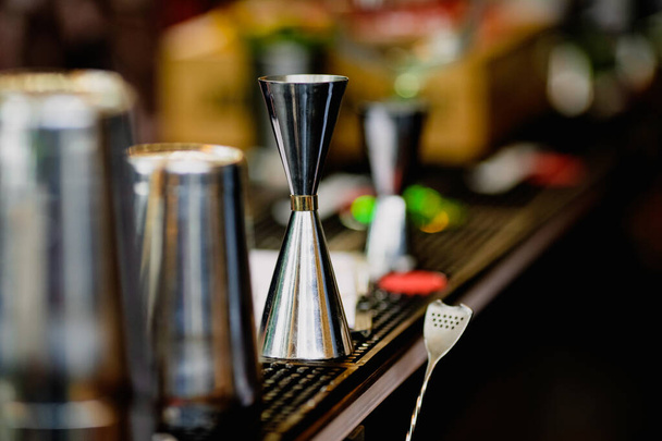 Shallow depth of field (selective focus) image with alcohol jiggers of a bartender on the counter of a bar. - Photo, Image