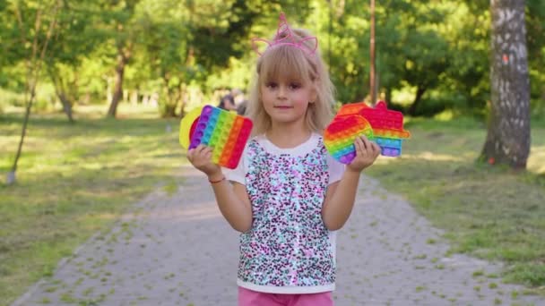Usmívající se dítě dívka dítě drží mačkání anti-stres pop it touch screen hračky jednoduchá hra dolíčky - Záběry, video