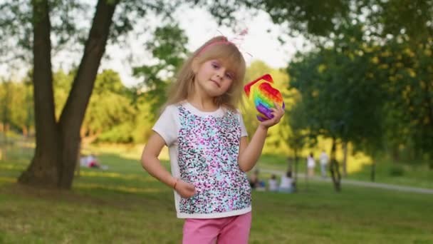 Ragazza bambino che tiene molte bolle di silicone squishy colorate pop it giocattoli sensoriali popolari, pollice in su - Filmati, video
