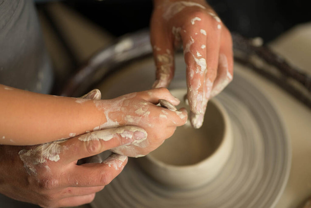 le mani umane fanno un prodotto di argilla su una ruota di vasai - Foto, immagini
