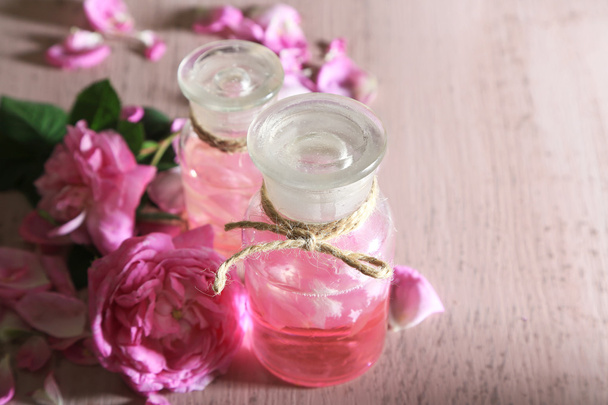 Rose oil in bottle on color wooden background - Foto, afbeelding