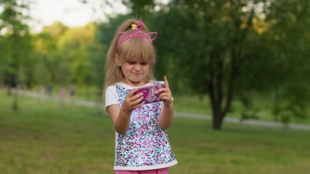 Ребенок девочка проигрывает на мобильный телефон игра, использовать мягкий силикон анти-стресс поп игрушку, чтобы успокоиться - Кадры, видео