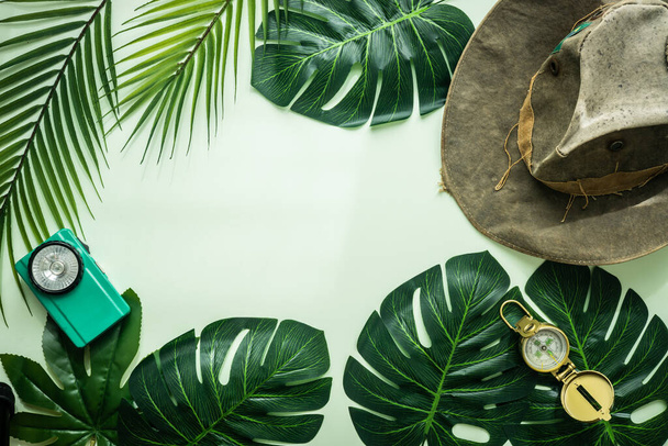 Hojas tropicales, sombrero de vaquero, brújula linterna vieja, estilo retro, diseño mínimo, concepto de viaje, fondo verde pastel en blanco  - Foto, Imagen