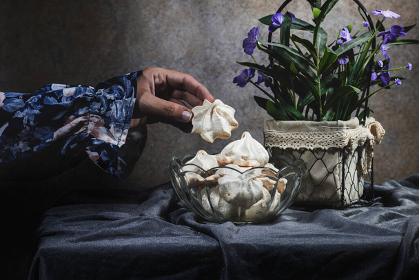 dark effect, closeup hand with beautiful dress eating French dessert Meringue prepared from whipped with sugar and baked eggs - Foto, Imagen