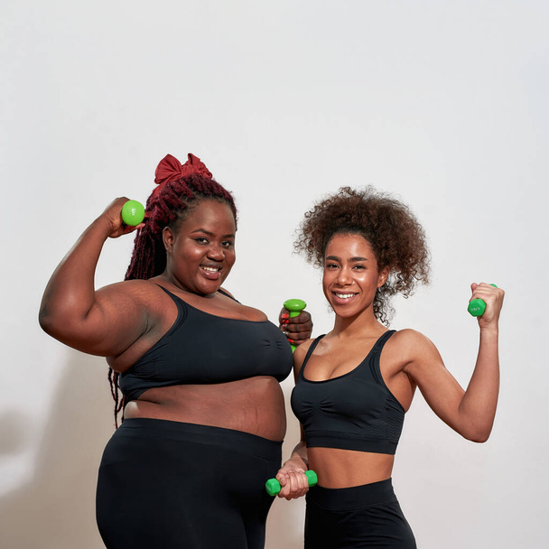 Picture of two afro women holding dumbbells  - Фото, изображение