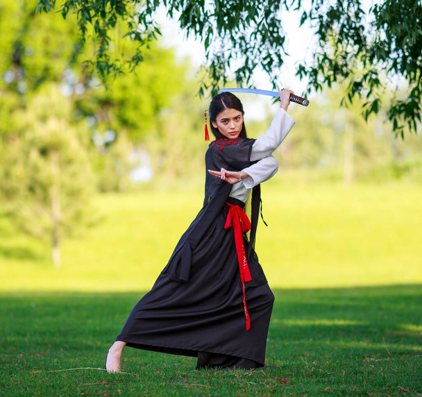 Young asian woman in traditional kimono trains fighting techniques with katana sword, samurai warrior girl - Φωτογραφία, εικόνα