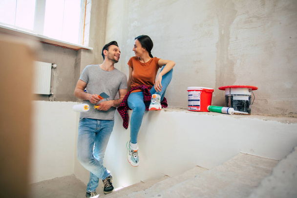 Modern happy young couple in love in casual clothes during new home repair or renovation of walls with a lot of tools for this - Photo, image