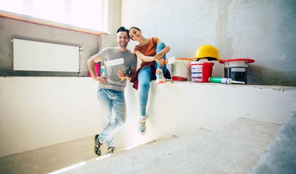 Modern happy young couple in love in casual clothes during new home repair or renovation of walls with a lot of tools for this - Photo, Image
