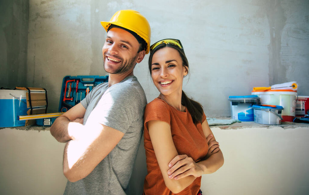 Modern happy young couple in love in casual clothes during new home repair or renovation of walls with a lot of tools for this - Zdjęcie, obraz