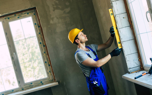 Young home repair male or worker busy with house renovation, holds building equipment, wears casual working clothes in the new build - Foto, Bild