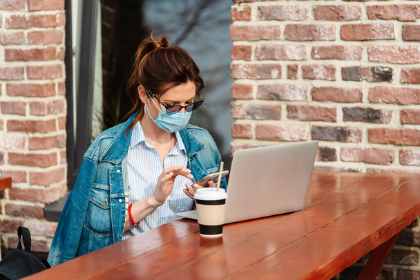 Een jonge vrouw werkt op afstand op een laptop tijdens de Covid-19 pandemie - Foto, afbeelding