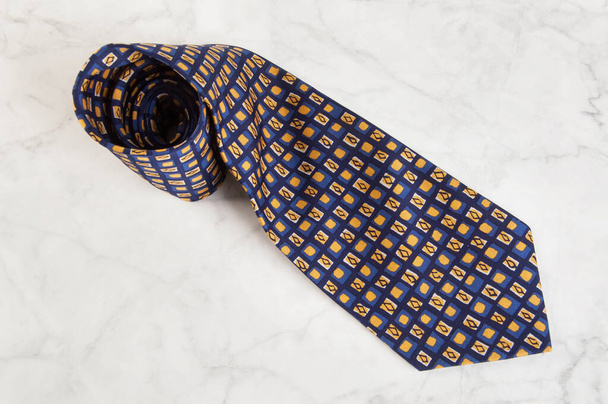 Blue neck tie with geometric pattern on marble background. Copy space for text. - Фото, зображення