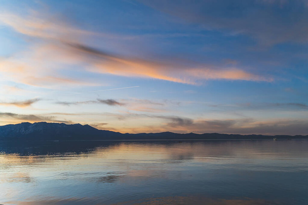 Barevné mraky odrážející se ve vodě nad jezerem Tahoe California po západu slunce - Fotografie, Obrázek