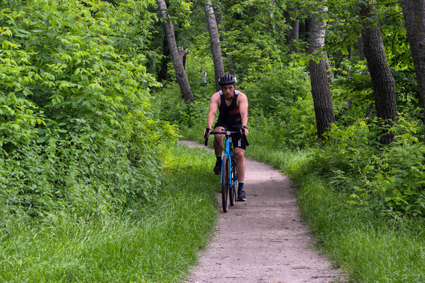 POLTAVA, UKRAINE - 19 Haziran 2021: Bisikletçiler yaz öğleden sonraları triatlon yarışmaları sırasında parkta bisiklet sürerler - Fotoğraf, Görsel