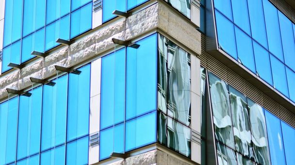 Abstrakte Nahaufnahme der mit Glas verkleideten Fassade eines modernen Gebäudes, das mit reflektierendem Plattenglas überzogen ist. Architektur abstrakten Hintergrund. Detail Glaswand und Fassade. - Foto, Bild