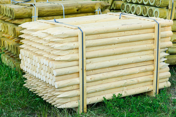 pallet with long round natural wooden fence posts with a sharpened tip - Foto, Imagen