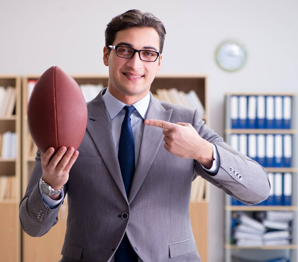 Бизнесмен с американским футболом в офисе - Фото, изображение