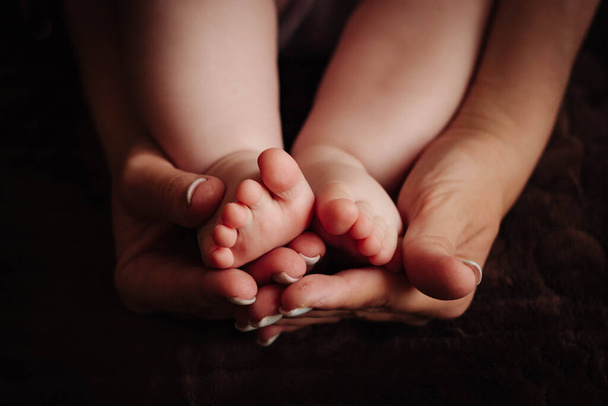 Childrens feet in the hands of the mother. - Foto, afbeelding