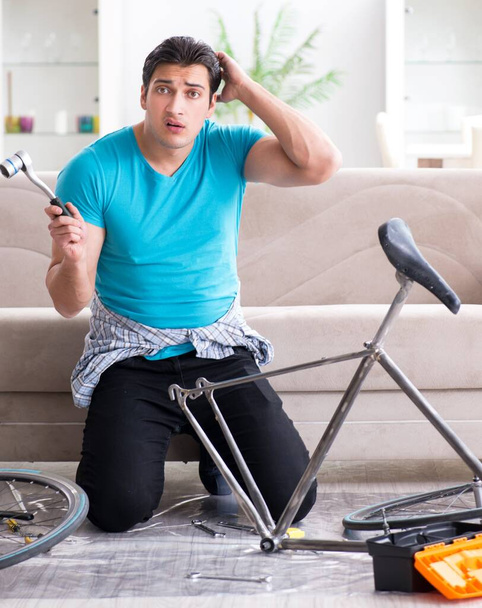 Jeune homme réparer vélo à la maison - Photo, image