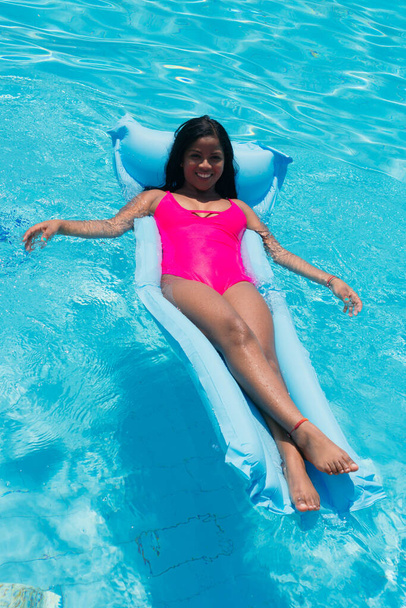 Menina africana sorridente nova no biquíni que se diverte no inflável na piscina - Foto, Imagem