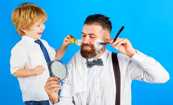 お父さんのアシスタント。息子と父親が髭を剃る。バーバーショップ。髭のケアだ。小さな床屋. - 写真・画像