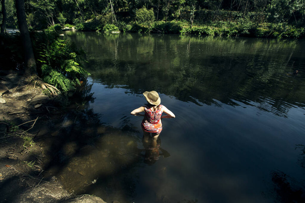 Žena stojící po pás ve vodě lesní řeky v hornaté oblasti.  - Fotografie, Obrázek