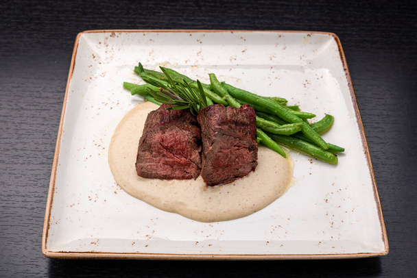 Filet mignon with asparagus on a light plate, on a dark background - Foto, imagen