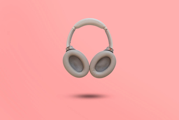 a simple wireless headphones isolated floating in the air against the colorful background - Photo, Image