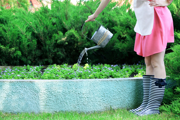 Young woman in rubber boots holding watering can, outdoors - Foto, Imagen