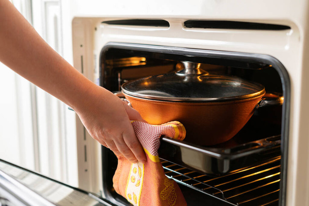 uma mulher close-up mãos abrir o forno e tirar alimentos frescos cozidos em casa - Foto, Imagem