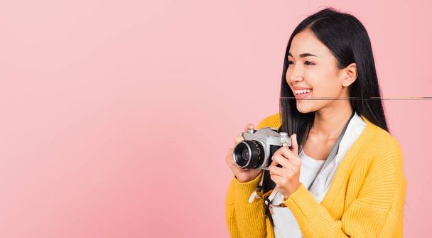 Привабливий щасливий азіатський стиль життя прекрасна молода жінка схвильована посміхаючись фотограф тримає ретро вінтажний фотоапарат готовий знімати ізольовано на рожевому фоні, туризм і концепцію відпустки - Фото, зображення