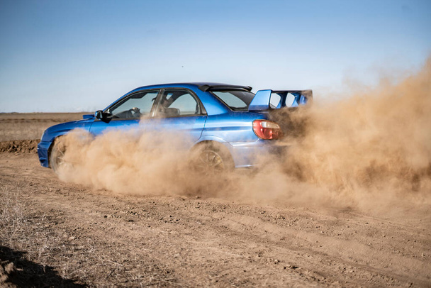 раллийный спортивный автомобиль, движущийся по гравийной гонке, быстрая скорость с брызгами грязи - Фото, изображение