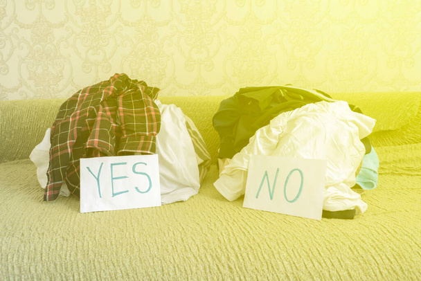 καθαρισμός και διαλογή των ρούχων, δύο σωρός υφάσματος. επιλέξτε ναι ή όχι - Φωτογραφία, εικόνα