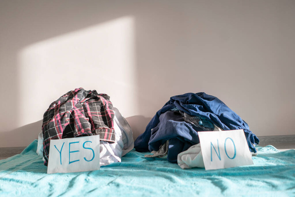 καθαρισμός και διαλογή των ρούχων, δύο σωρός υφάσματος. επιλέξτε ναι ή όχι - Φωτογραφία, εικόνα