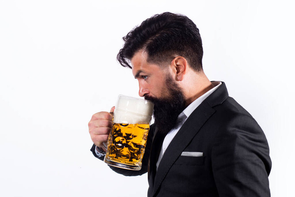 Hombre de traje clásico bebiendo cerveza. Tipo barbudo en traje de negocios se ve feliz y satisfecho. Retrato del hombre con copa alta de cerveza levantada isoalted en blanco. - Foto, imagen