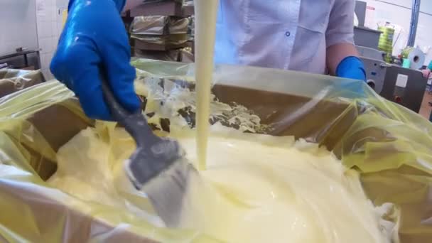 Le beurre est versé dans une boîte à la crémerie. Gros plan d'un tourbillon de crème liquide fondue. - Séquence, vidéo