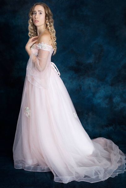 Une belle femme blonde dans une robe rose style princesse avec un long train - Photo, image