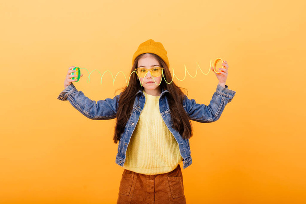 Una chica con camisa multicolor sostiene un juguete pegajoso multicolor en sus manos - Foto, imagen