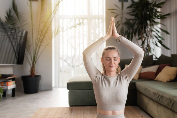 Beyaz tenli güzel bir kadın evde egzersiz yapıyor ve yoga yapıyor. Oturma odasında, meditasyon yapıyor ve dinleniyor. Yüksek kalite fotoğraf - Fotoğraf, Görsel