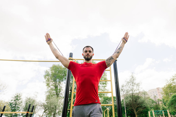 Caucasian sportsman pulling up wide grip hand on crossbar during street workout. Healthy lifestyle and street sport concept - Photo, Image