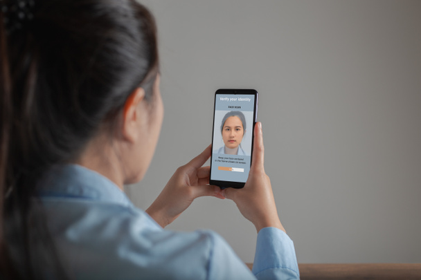 Aasialainen nainen skannaus kasvot kasvojentunnistusjärjestelmä älypuhelimeen tarkistaa henkilöllisyys, Tarkista henkilöllisyytesi, Biometrinen todentaminen ja kasvojentunnistus käsite. - Valokuva, kuva