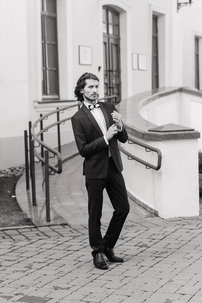 Handsome fashion businessman model dressed in an elegant suit and posing on street. Metrosexual - Foto, Bild