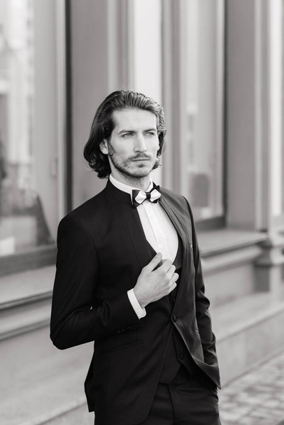 Handsome fashion businessman model dressed in an elegant suit and posing on street. Metrosexual - Fotografie, Obrázek