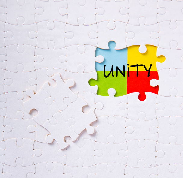 Κομμάτια παζλ που συνδέονται μεταξύ τους με τη λέξη ενότητα. Έννοια της ενότητας, της συνέργειας, της ολοκλήρωσης ή της αλληλεγγύης. - Φωτογραφία, εικόνα