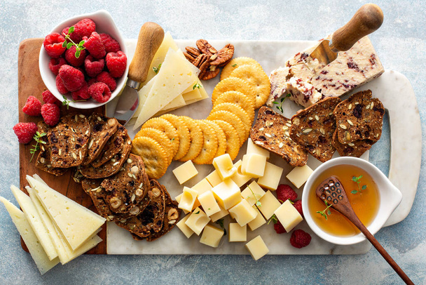 Cheese and snacks board with raspberry and crackers - Fotografie, Obrázek